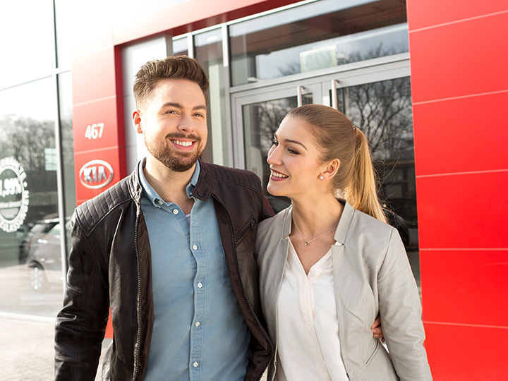 Satisfied customers walking out of Kia dealership